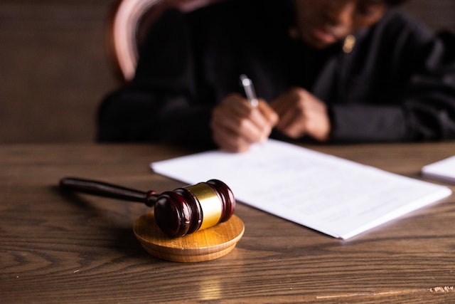 a judge out of focus writing on paper behind a gavel